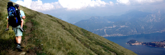 Hiker with child on back in mountains above Griante Lake Como